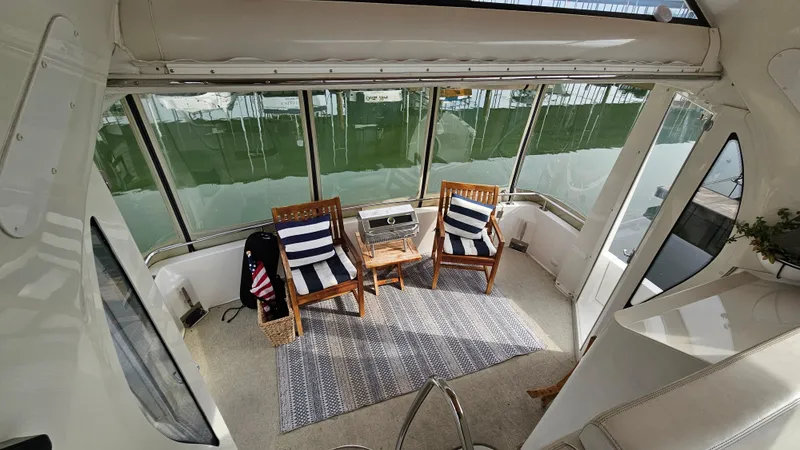 Slide: The Image of 2002 Carver 396 Motor Yacht interior with chairs, striped cushions, and a small table. - 6