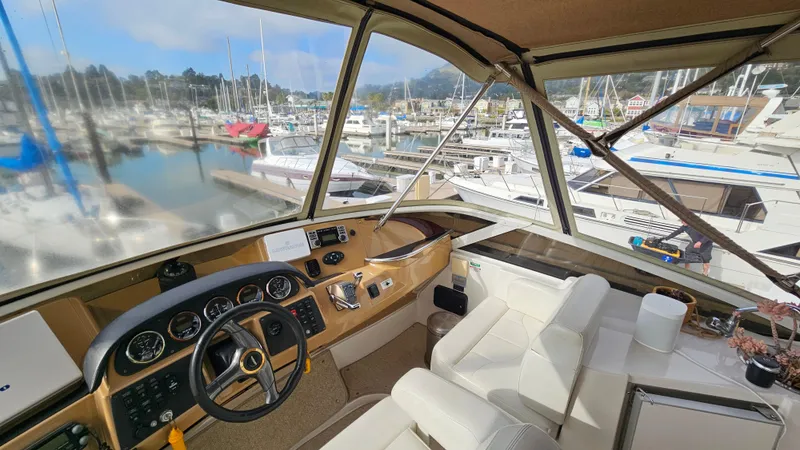 Slide: The Image of 2002 Carver 396 Motor Yacht helm with marina view, featuring white seating and control panel. - 5