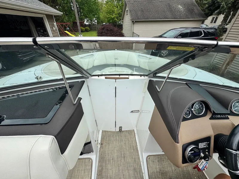 Slide: The Image of 2016 Cobalt 200S boat interior with dashboard and seating, parked near garages. - 13