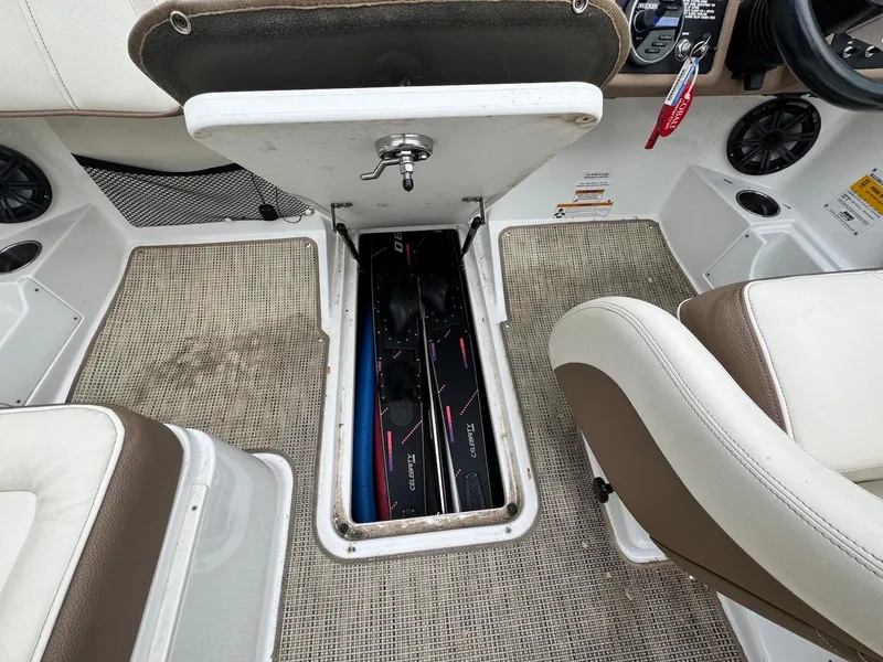 Slide: The Image of 2016 Cobalt 200S boat interior with open storage compartment, beige seats, and carpeted floor. - 17
