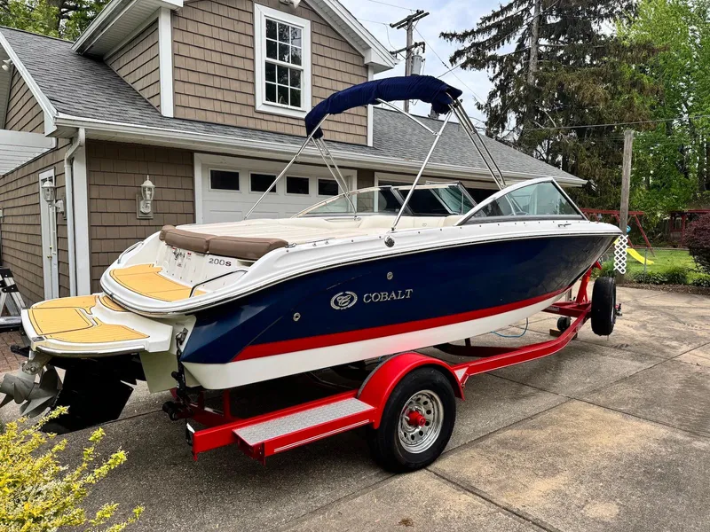 Slide: The Image of 2016 Cobalt 200S boat on red trailer parked in driveway near garage. - 2