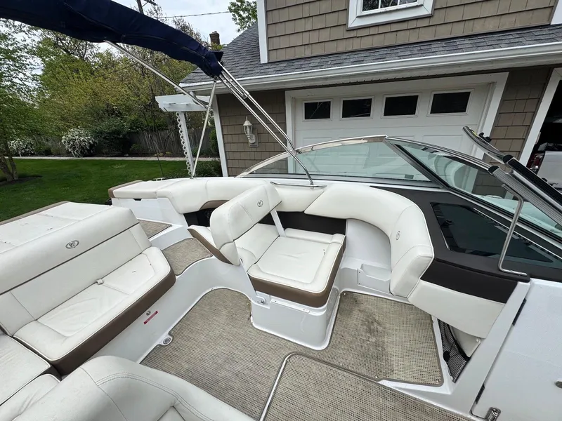 Slide: The Image of 2016 Cobalt 200S boat with white seating and beige flooring, parked near a garage. - 7