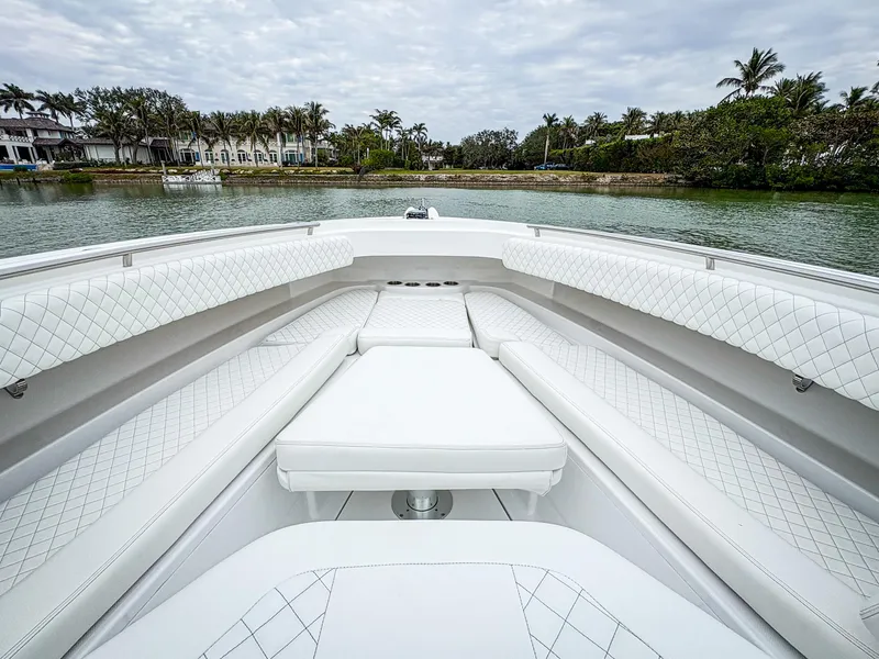 Slide: The Image of 2023 HCB 42 Lujo boat interior with luxurious white seating, docked near tropical shoreline. - 24