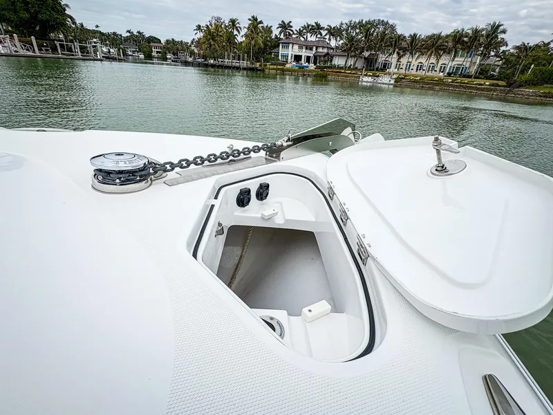 Slide: The Image of 2023 HCB 42 Lujo boat anchor compartment with open hatch, docked near waterfront homes. - 35