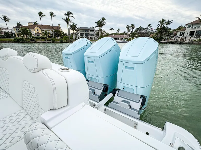 Slide: The Image of 2023 HCB 42 Lujo boat with triple outboard engines on a scenic waterfront. - 36