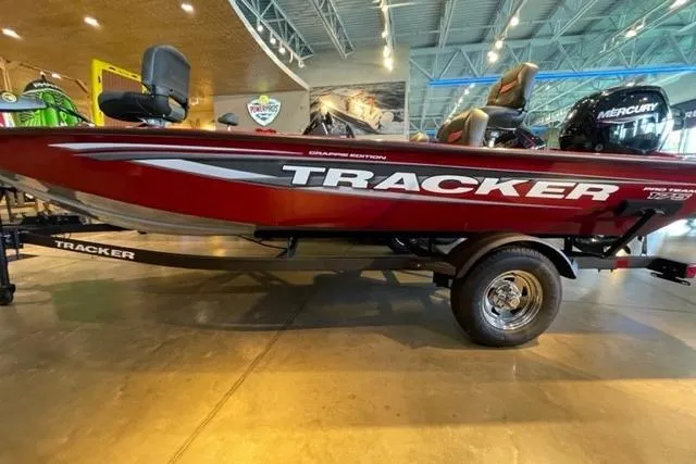 The Image of 2025 Tracker Pro Team 175 Crappie Edition boat displayed indoors, red with Mercury engine. - 0