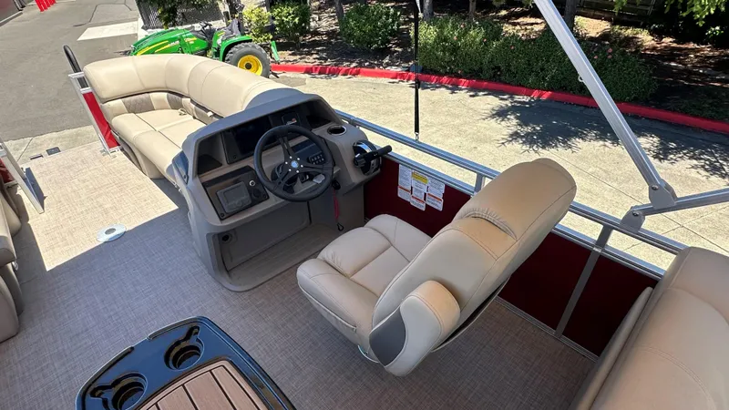 Slide: The Image of 2025 Sun Tracker Party Barge 22 DLX interior with beige seating and steering console. - 2