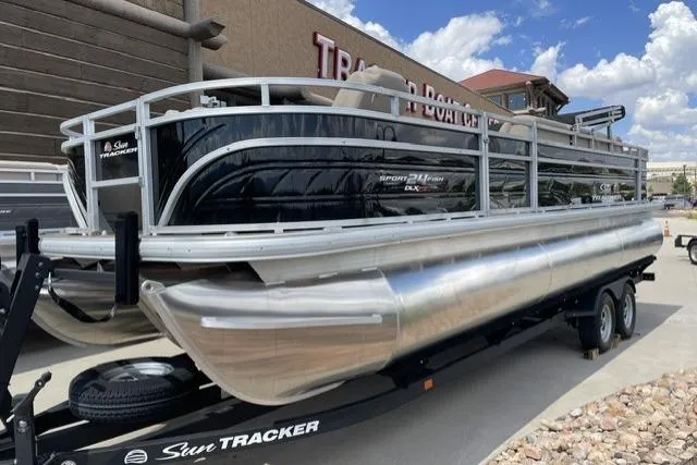 The Image of 2025 Sun Tracker Sportfish 24 XP3 pontoon boat on trailer, parked outdoors. - 0