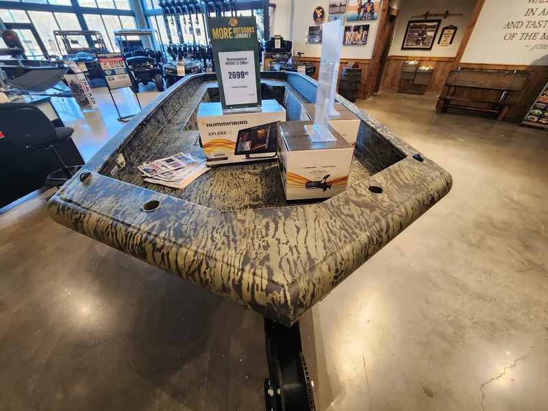 Slide: The Image of 2025 Tracker Grizzly 1650 T Prairie Wings Edition boat displayed in showroom with accessories. - 2