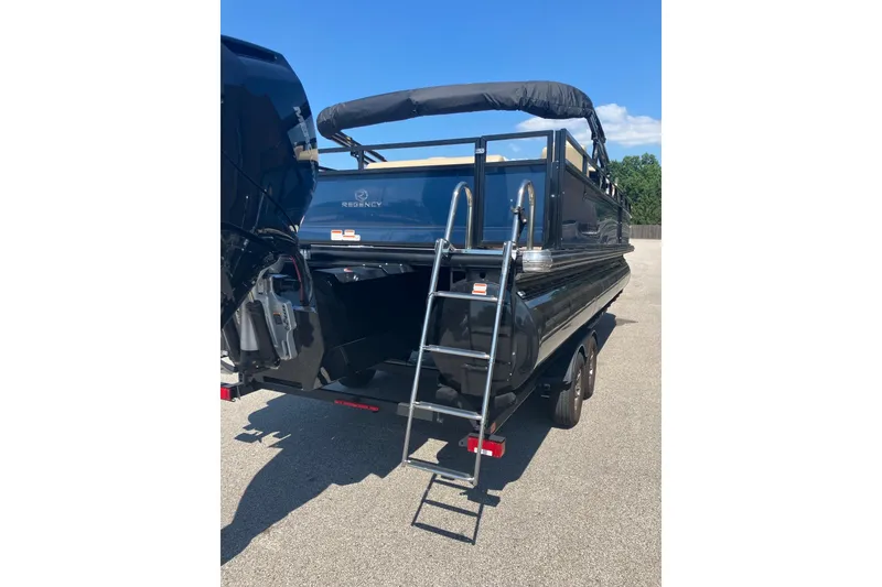 Slide: The Image of 2025 Regency 250 DL3 pontoon boat with ladder, parked on pavement. - 7