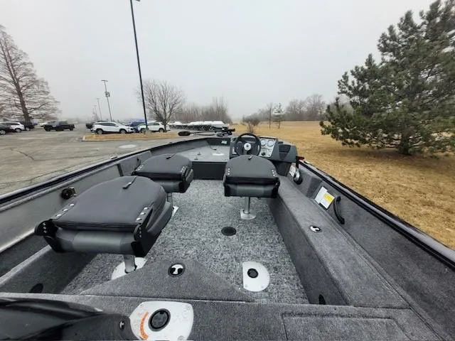 Slide: The Image of 2025 Tracker Pro Guide V-16 SC boat interior with seating and controls, parked outdoors. - 4