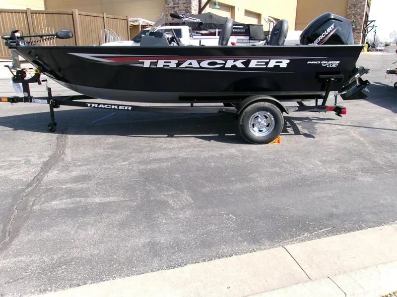 Slide: The Image of 2025 Tracker Pro Guide V-16 SC boat on trailer, parked outdoors. - 2