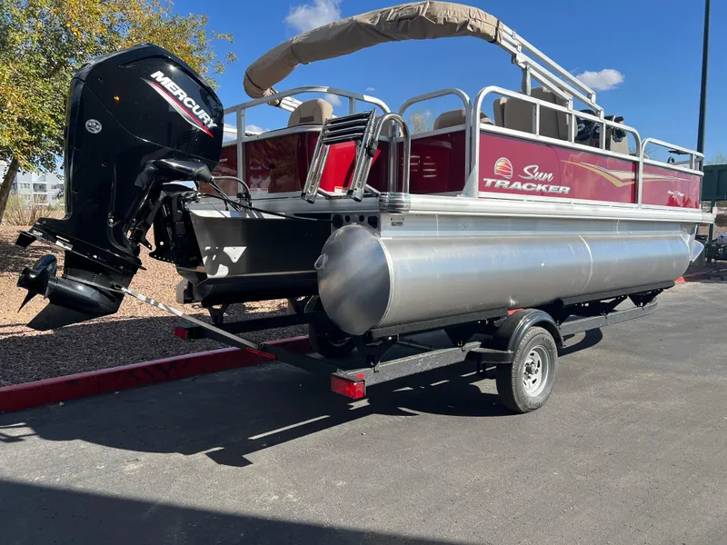 Slide: The Image of 2025 Sun Tracker Bass Buggy 18 DLX pontoon boat on trailer, featuring Mercury outboard motor. - 2