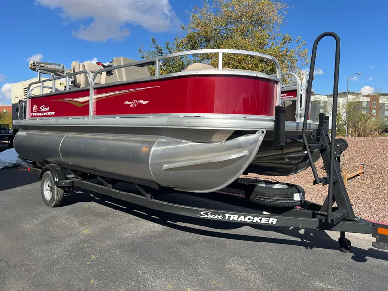 Slide: The Image of 2025 Sun Tracker Bass Buggy 18 DLX pontoon boat on trailer, parked outdoors. - 3