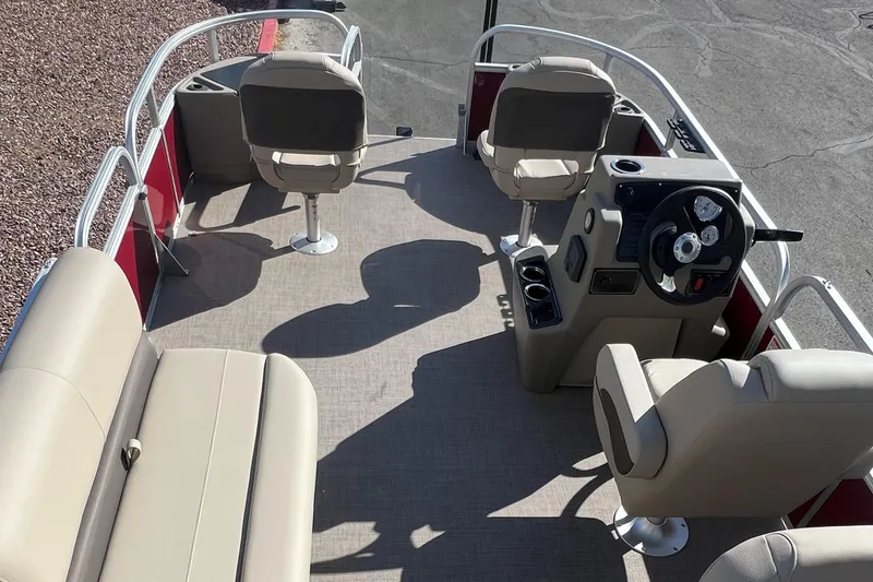 Slide: The Image of 2025 Sun Tracker Bass Buggy 18 DLX pontoon boat interior with beige seating and steering console. - 6