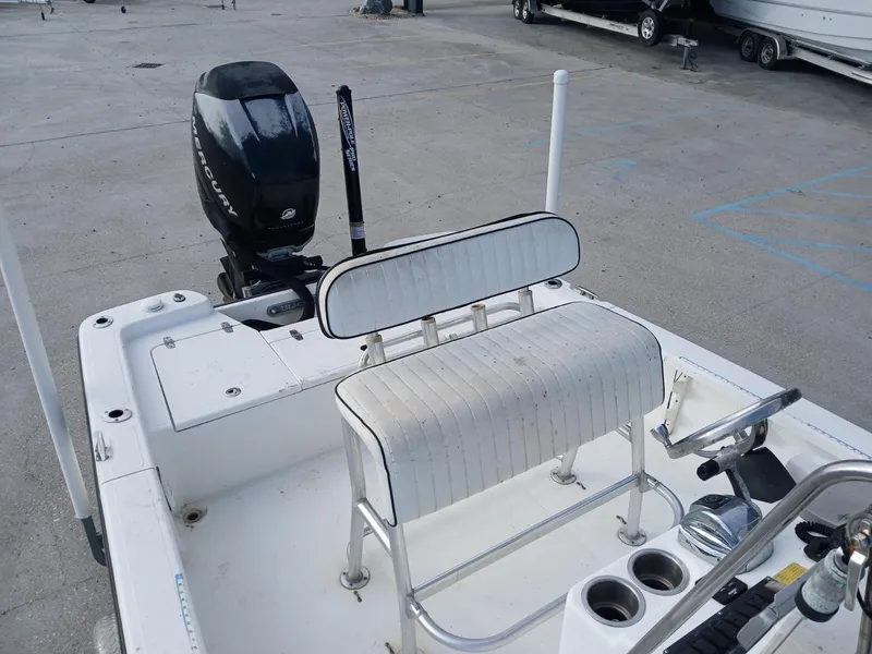 Slide: The Image of 2005 BlackJack 224 boat interior with seating and motor, docked on concrete surface. - 2