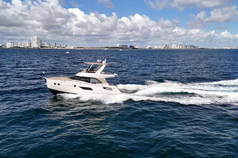 Slide: The Image of 2014 Carver 40 Command Bridge yacht cruising on open water with city skyline backdrop. - 18