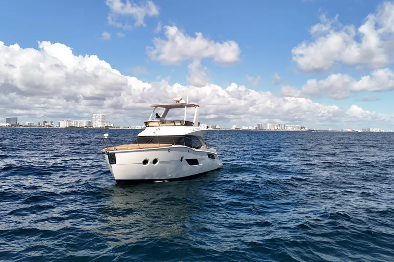 Slide: The Image of 2014 Carver 40 Command Bridge yacht on open sea with city skyline backdrop. - 6