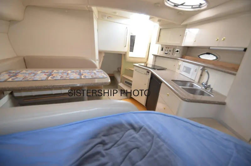 Slide: The Image of 1999 Maxum 3300 SCR cabin interior with kitchenette, seating, and sleeping area. - 7