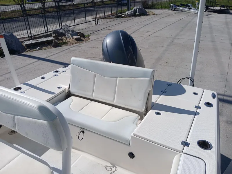 Slide: The Image of 2018 Robalo 226 Cayman boat interior with seating and motor, parked on concrete. - 4