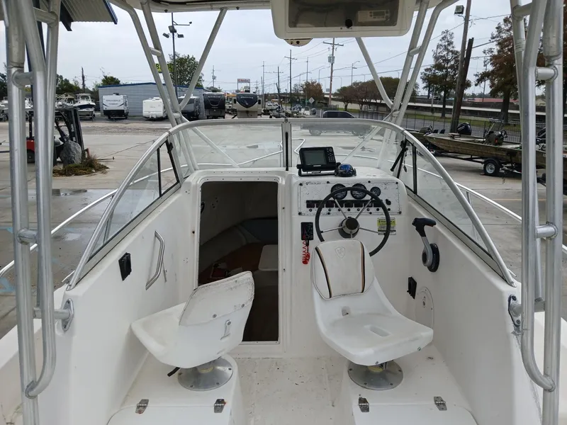 Slide: The Image of 1999 Century 2300 boat interior with steering wheel and seats, parked in a marina. - 3