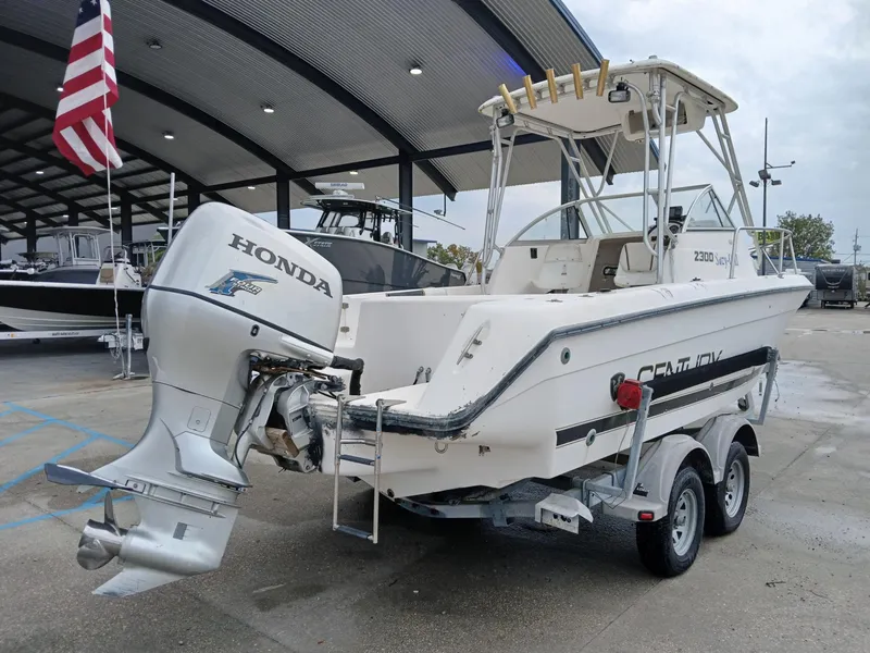 Slide: The Image of 1999 Century 2300 boat with Honda outboard motor on trailer, parked under a canopy. - 8
