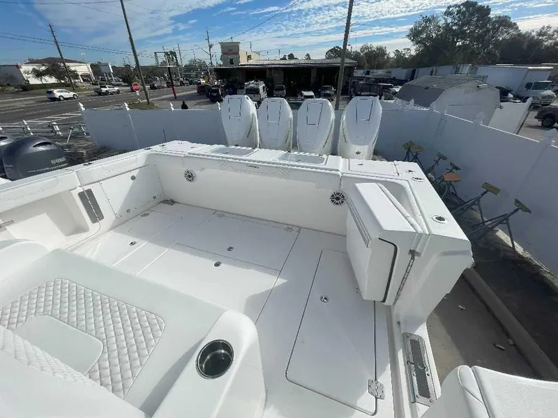 Slide: The Image of 2024 Caymas 401 CC boat deck with multiple outboard engines, white interior, and urban background. - 19