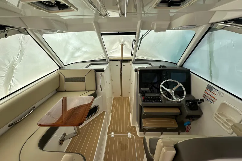 Slide: The Image of 2019 Pursuit DC 325 Dual Console interior with helm, seating, and wooden table. - 39