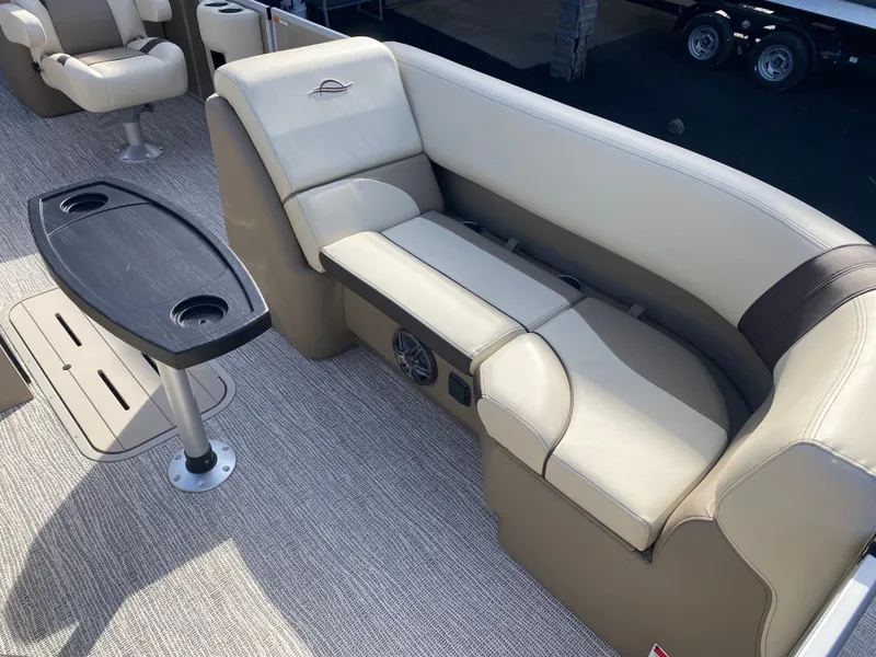 Slide: The Image of 2025 SunCatcher Select 322RC boat interior with beige seating and a black table. - 22