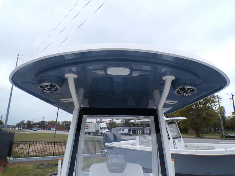 Slide: The Image of 2024 Parker 2400 Center Console boat with T-top and speakers, parked outdoors. - 12