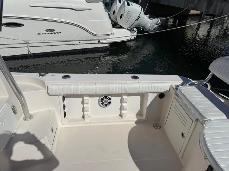 Slide: The Image of 2006 Cobia 250 Walk-Around boat interior, featuring seating and storage, docked near water. - 16