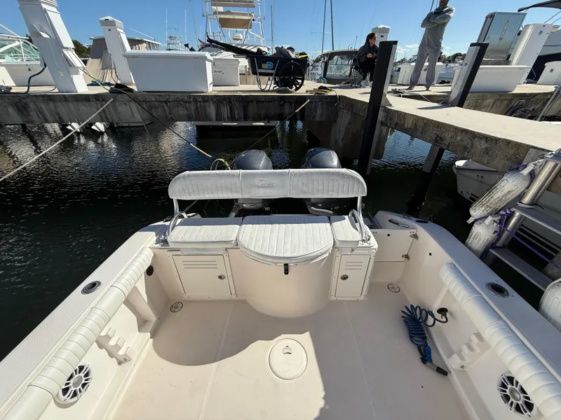 Slide: The Image of 2006 Cobia 250 Walk-Around boat docked, featuring spacious seating and dual outboard motors. - 18