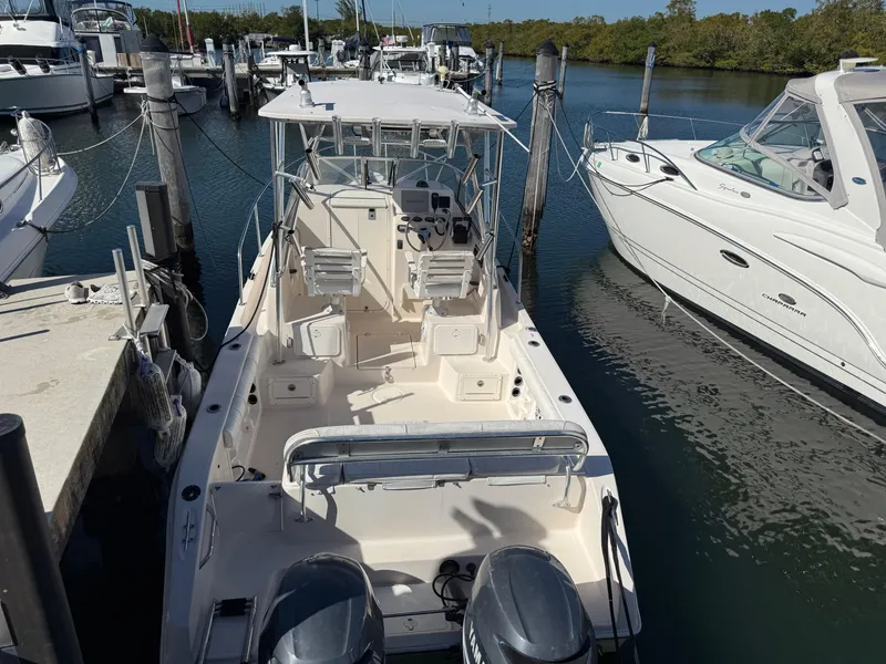 Slide: The Image of 2006 Cobia 250 Walk-Around boat docked, featuring dual engines and spacious deck. - 4