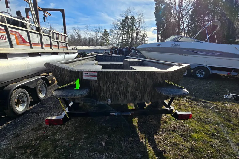 Slide: The Image of 2025 SeaArk DXS 1860 SLD boat on trailer, parked outdoors with other boats. - 3