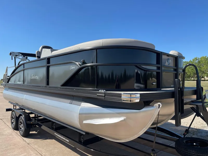 Slide: The Image of 2024 Barletta Cabrio 22UC pontoon boat on trailer, sleek black design, sunny day. - 16