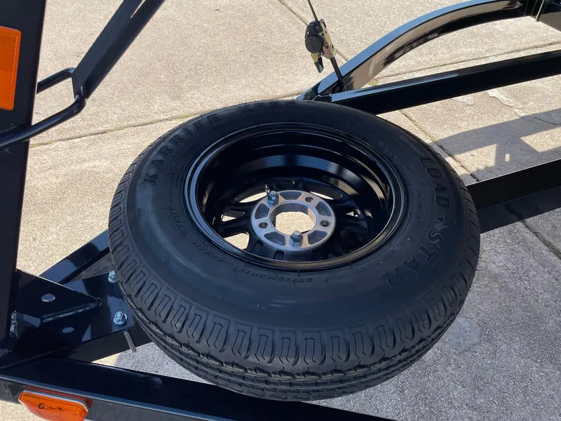 Slide: The Image of 2024 Barletta Cabrio 22UC trailer with mounted spare tire on black rim. - 22