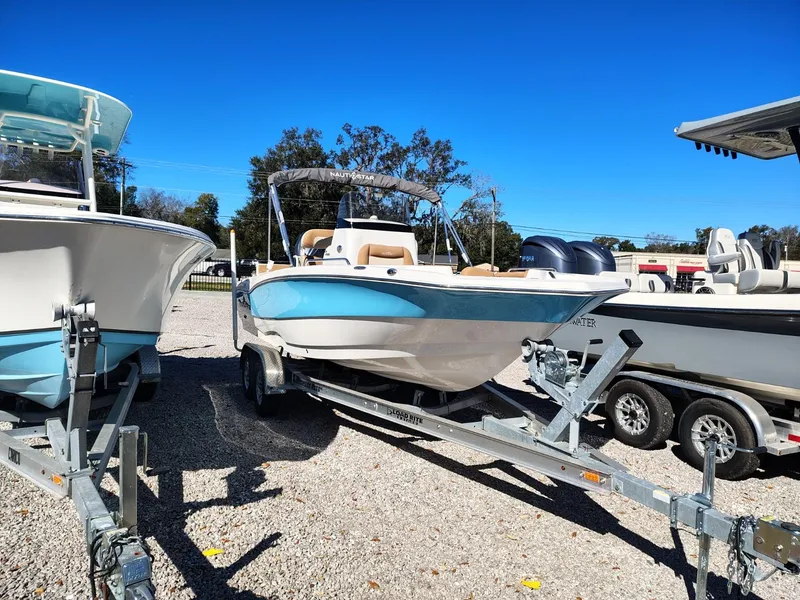 The Image of 2024 NauticStar 211 Hybrid boat on trailer, displayed outdoors under clear blue sky. - 0