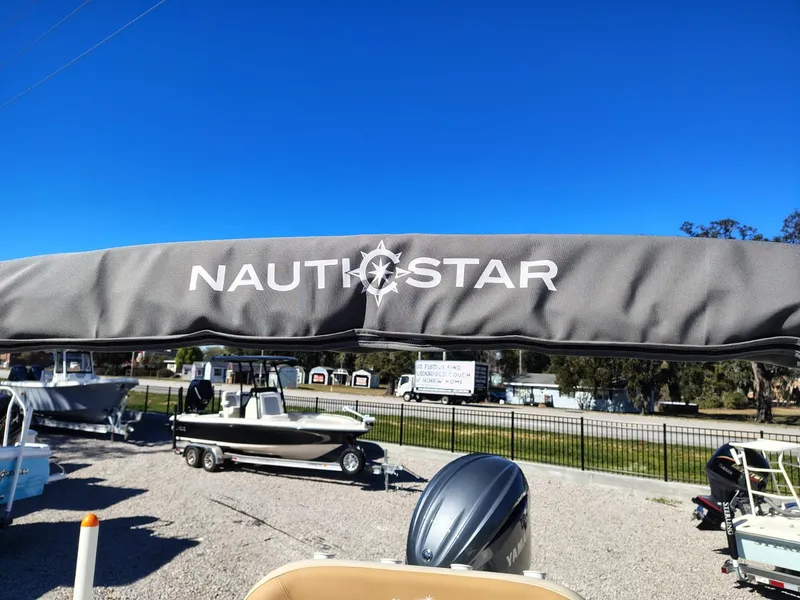 Slide: The Image of 2024 NauticStar 211 Hybrid boat with canopy, displayed outdoors under clear blue sky. - 14