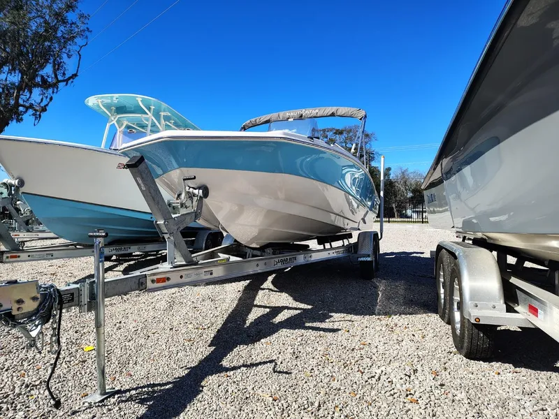 Slide: The Image of 2024 NauticStar 211 Hybrid boat on trailer, displayed outdoors under clear blue sky. - 16
