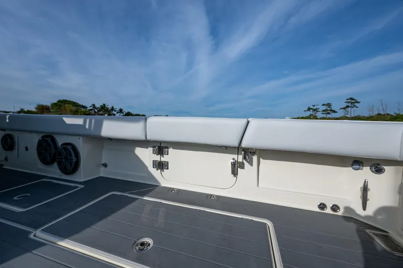 Slide: The Image of 2017 HCB 53 boat deck with cushioned seating and speakers under a clear blue sky. - 8