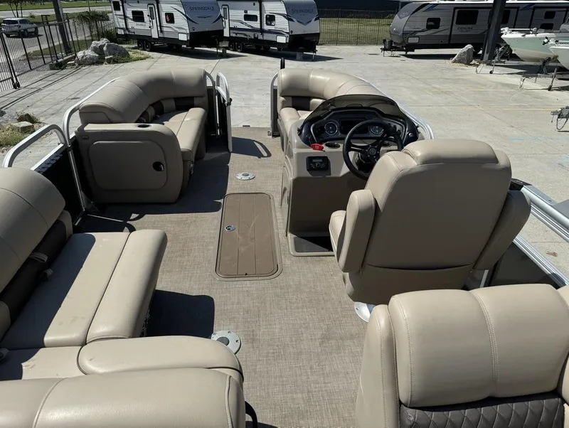 Slide: The Image of 2023 Sun Tracker Party Barge 22 DLX interior with beige seating and steering console. - 16