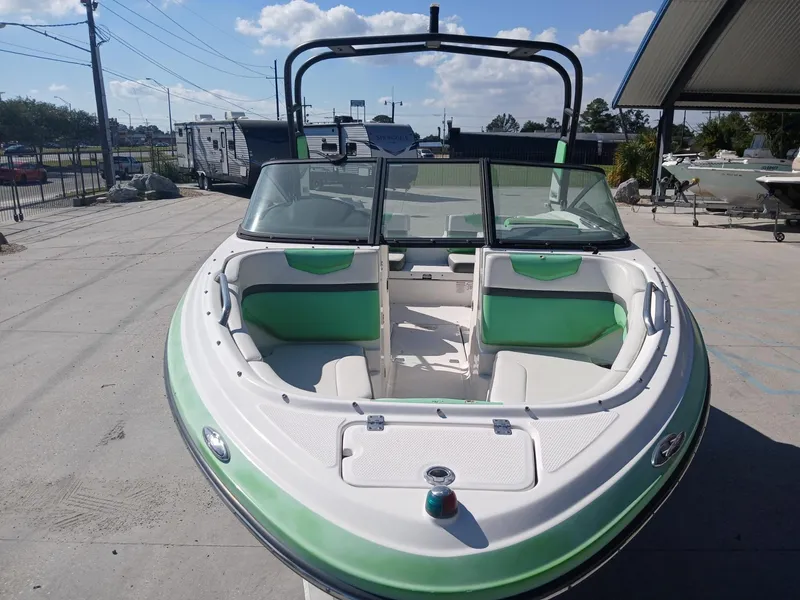 Slide: The Image of 2016 Chaparral 203 Vortex boat with green and white interior, parked outdoors. - 7