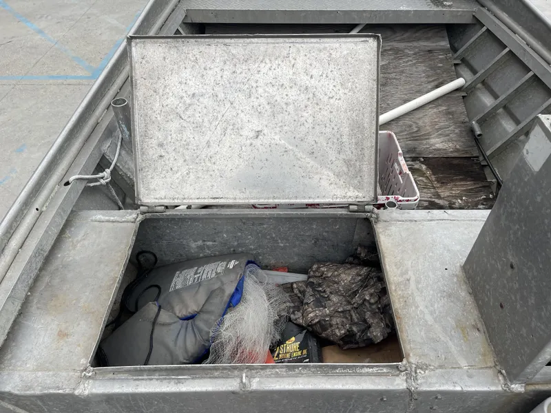 Slide: The Image of Open storage compartment on a 1991 Custom 18ft boat, containing fishing gear and supplies. - 13
