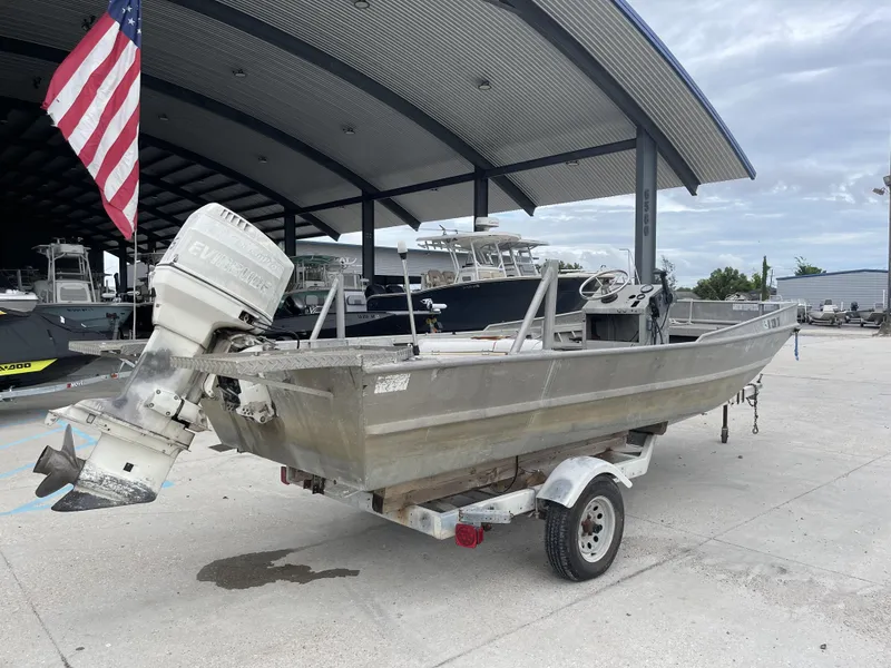 Slide: The Image of 1991 Custom 18ft boat on trailer, parked under a canopy with an American flag. - 8
