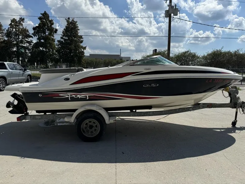 Slide: The Image of 2011 Sea Ray 185 Sport boat on trailer, parked outdoors under a cloudy sky. - 1