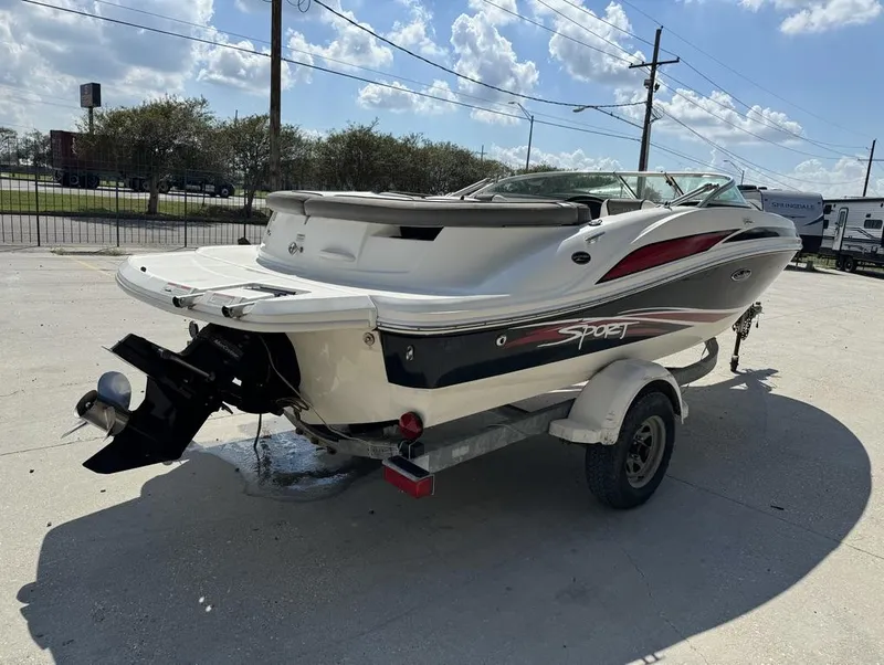 Slide: The Image of 2011 Sea Ray 185 Sport boat on trailer, parked outdoors under a sunny sky. - 2