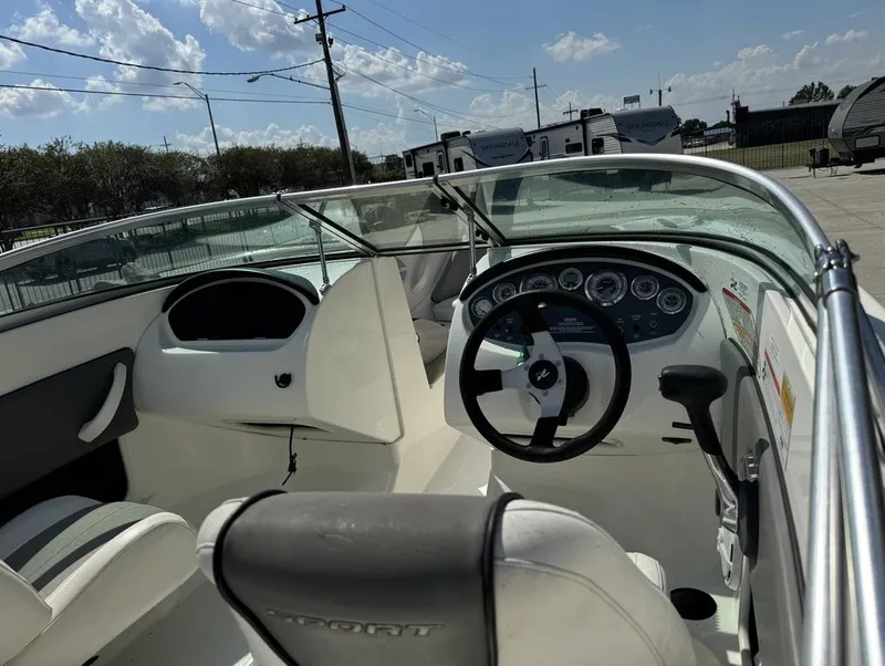 Slide: The Image of 2011 Sea Ray 185 Sport boat interior with steering wheel and dashboard under sunny skies. - 7