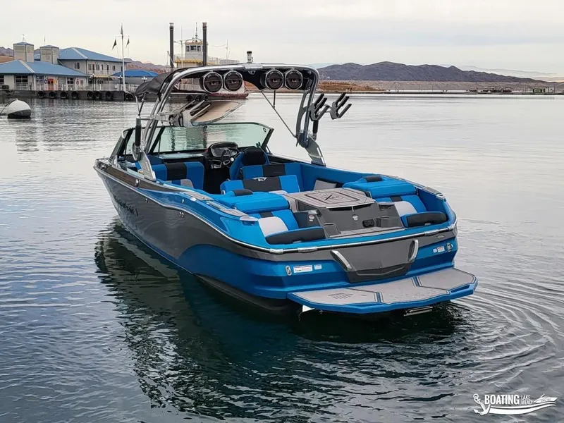 Slide: The Image of 2021 MasterCraft X26 boat on calm water near a marina. - 11