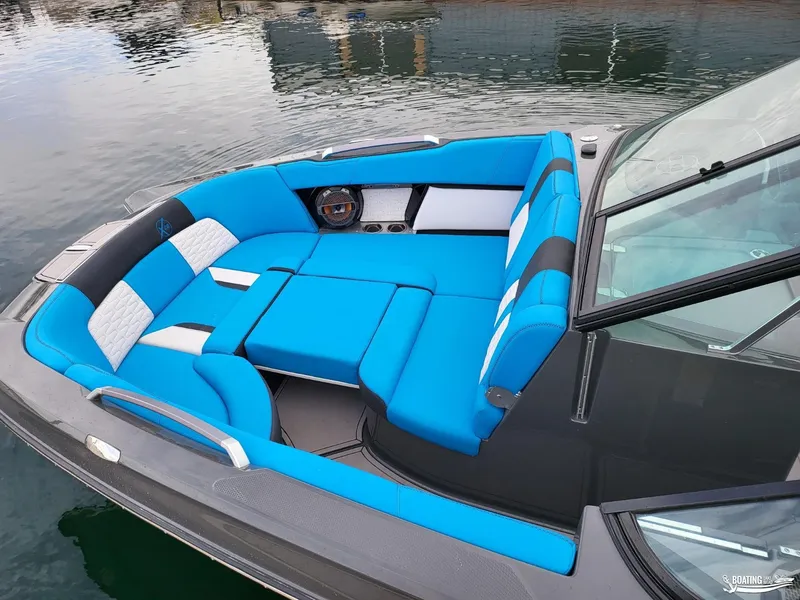 Slide: The Image of 2021 MasterCraft X26 boat with blue and white seating on calm water. - 14
