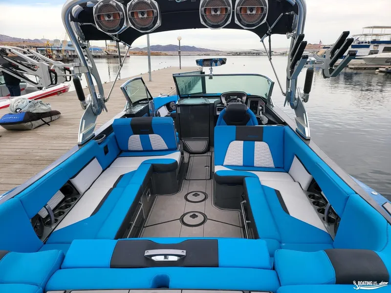 Slide: The Image of 2021 MasterCraft X26 boat interior with blue seating, docked by the water. - 16